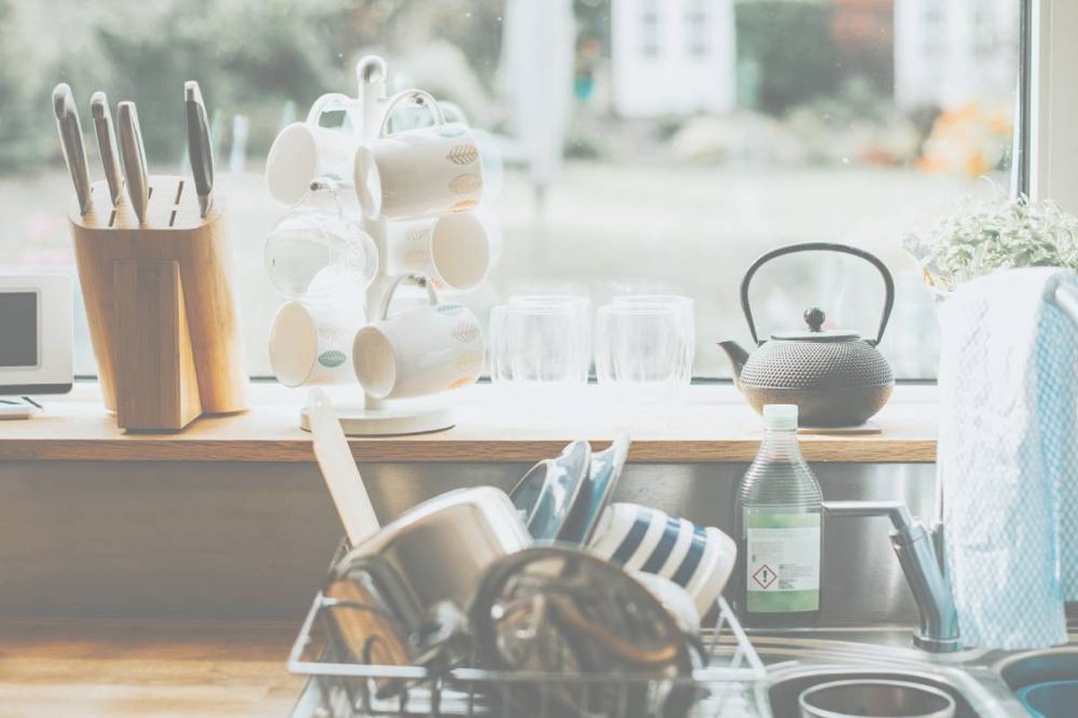 Sunny kitchen counter with dishes and a kettle
